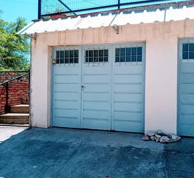 a pair of white garage doors on a house at Casa en Villa Carlos Paz in Villa Carlos Paz