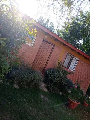 a red brick house with a door and some plants at Casa Sol y Rio in Mina Clavero