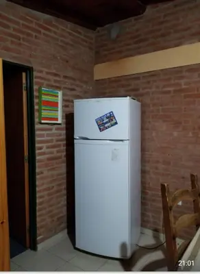 a white refrigerator in a room with a brick wall at Casa Sol y Rio in Mina Clavero