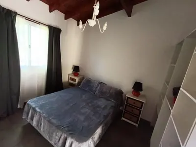 a bedroom with a bed and two night stands and a window at El Cuyanito Merlo in Merlo