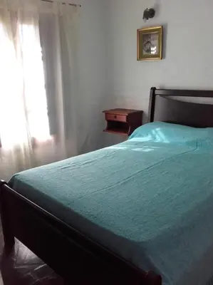 a bedroom with a bed with a blue blanket and a window at Al Sol de Traslasierra in Mina Clavero