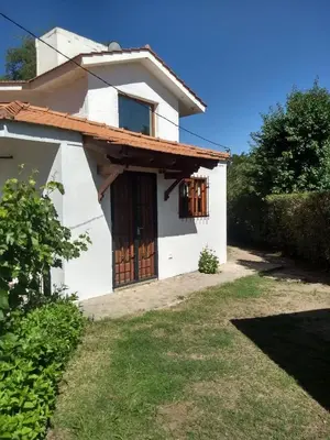 a white house with a gate and a yard at Al Sol de Traslasierra in Mina Clavero