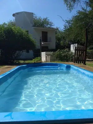a large blue swimming pool in front of a house at Al Sol de Traslasierra in Mina Clavero