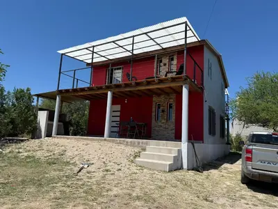 a red house with a balcony on top of it at Cabañas Campo y Río in San Lorenzo
