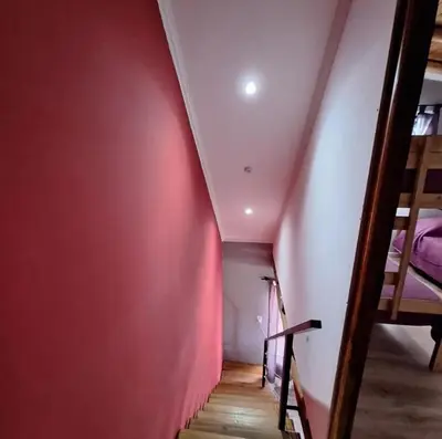 a room with a red accent wall and a staircase at Cabañas Campo y Río in San Lorenzo
