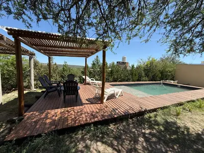 a wooden deck with a table and chairs next to a swimming pool at Cabañas Campo y Río in San Lorenzo