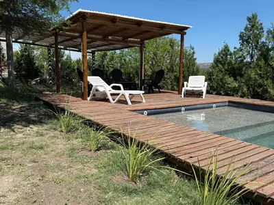 a wooden deck with two chairs and a swimming pool at Cabañas Campo y Río in San Lorenzo