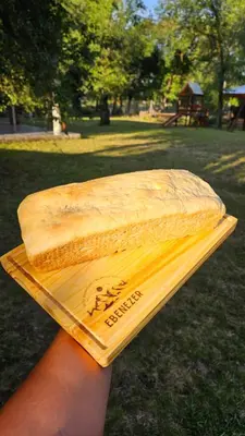a person holding a piece of bread on a cutting board at Complejo Ebenezer in San Ignacio