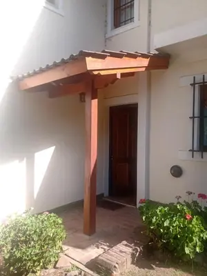 a wooden pergola on the side of a house at Casa La Escondida in Villa del Dique