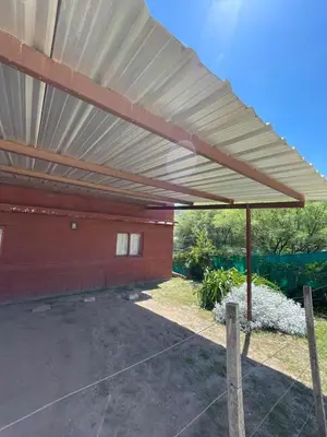 awning over a parking lot in front of a building at Cabañas El Pela in Villa Carlos Paz