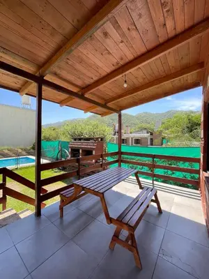 a wooden patio with a table and benches on a deck at Cabañas El Pela in Villa Carlos Paz