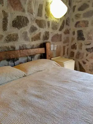 a bed in a room with a stone wall at Valle Iguana in San Lorenzo