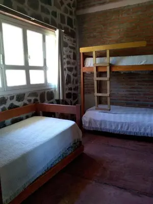 a bedroom with two bunk beds and a brick wall at Valle Iguana in San Lorenzo