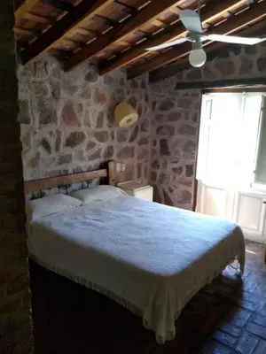 a bedroom with a large bed in a stone wall at Valle Iguana in San Lorenzo