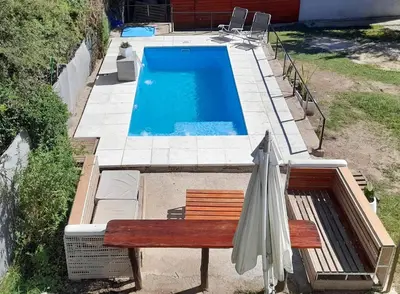 a swimming pool with a bench and an umbrella at Apartamento Jhaky in Villa Carlos Paz