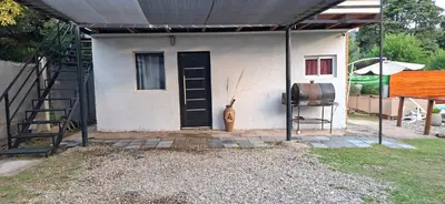 a small house with a black door and a staircase at Casa Jhaky in Villa Carlos Paz