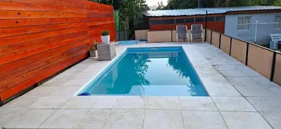 a swimming pool in a backyard with a wooden fence at Casa Jhaky in Villa Carlos Paz