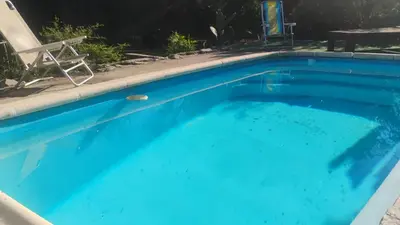 a blue swimming pool with a chair and a chaise lounge at CASA SAMARANA Alta Gracia in Alta Gracia