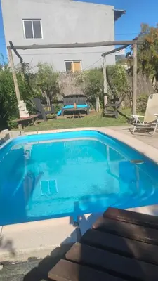 a blue swimming pool in front of a house at CASA SAMARANA Alta Gracia in Alta Gracia