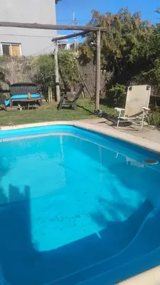 a blue swimming pool with a chair and a bench at CASA SAMARANA Alta Gracia in Alta Gracia