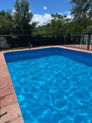 a blue swimming pool with a black fence at Departamento en Villa Carlos paz in Villa Carlos Paz