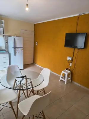 a kitchen with a table and chairs and a tv on a wall at Quique1 in Pilar