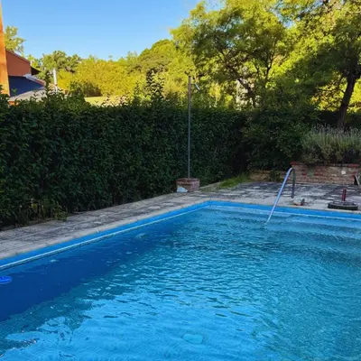 a swimming pool with blue water in a yard at Casa completa con piscina a 600 metros de plaza de Villa de las Rosas in Villa de Las Rosas