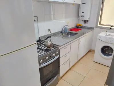 a kitchen with a stove and a sink and a washing machine at S rosa centro in Cordoba