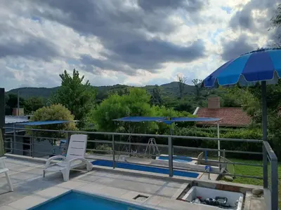 a patio with a pool and an umbrella and a chair at Aguaribay in Villa Los Aromos