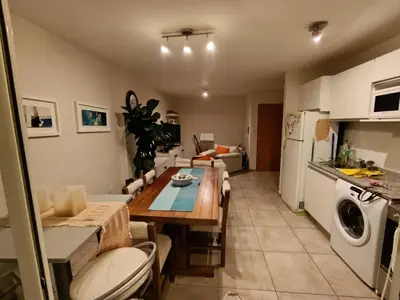a kitchen and living room with a table and a refrigerator at Dpto 1 dormitorio luminoso zona Nuevocentro in Cordoba