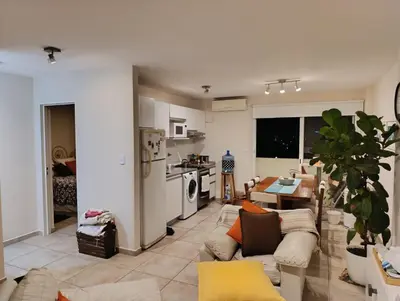a living room with a couch and a kitchen at Dpto 1 dormitorio luminoso zona Nuevocentro in Cordoba