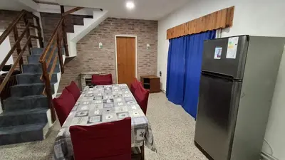 a room with a table with chairs and a refrigerator at El Balcón de la Costanera in Santa Rosa de Calamuchita