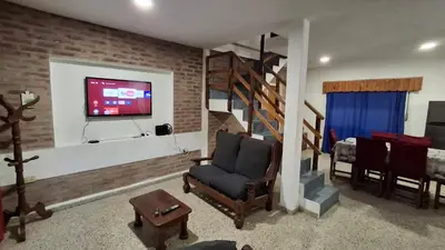 a living room with a couch and a tv on a brick wall at El Balcón de la Costanera in Santa Rosa de Calamuchita