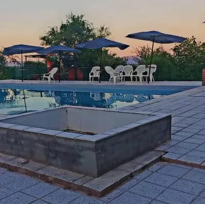 a swimming pool with tables and chairs and umbrellas at Alto de Balcón in Tanti