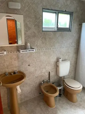 a bathroom with a toilet and a sink and a mirror at Areté Del Rio in Villa Carlos Paz