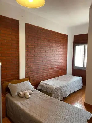 a bedroom with two beds and a brick wall at Areté Del Rio in Villa Carlos Paz