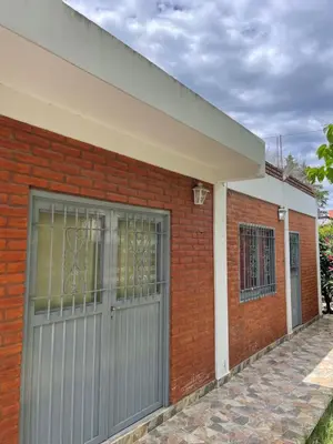 a brick house with a gray garage door at Areté Del Rio in Villa Carlos Paz