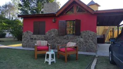 a red house with two chairs and a table at Casas de alquiler villa ciudad parque in Villa Ciudad Parque
