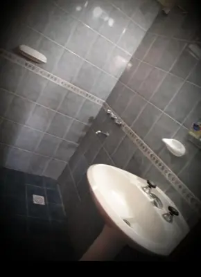 a bathroom with a white sink and gray tiled walls at Complejo gauna in Villa Carlos Paz