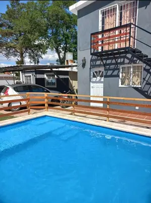 a blue swimming pool in front of a house at Complejo gauna in Villa Carlos Paz
