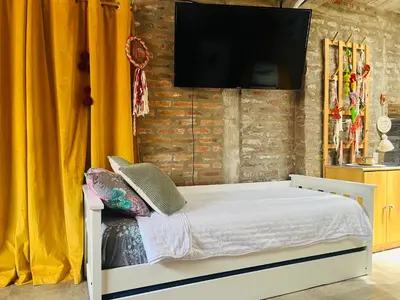 a bedroom with a bed with a television on a brick wall at Monoambiente luminoso y equipado, ubicado en zona céntrica in Cordoba