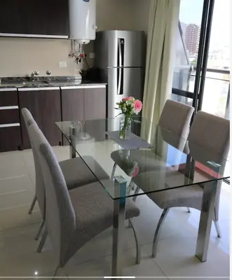 a glass table and chairs in a kitchen at DEPARTAMENTO con PILETA CENTRO CARLOS PAZ in Villa Carlos Paz