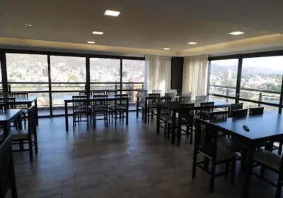 a restaurant with tables and chairs and large windows at DEPARTAMENTO con PILETA CENTRO CARLOS PAZ in Villa Carlos Paz