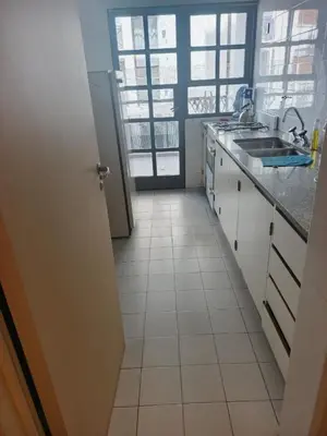 a kitchen with white tile floors and a sink at Departamento 2 dorm frente patio olmos in Cordoba