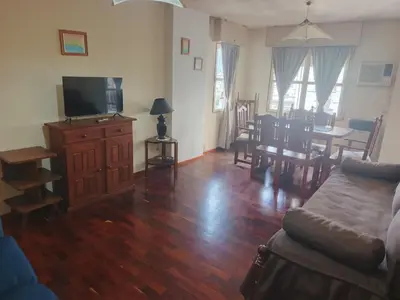 a living room with a couch and a television and a table at Departamento 2 dorm frente patio olmos in Cordoba