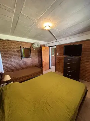 a bedroom with a yellow bed and a flat screen tv at Departamento Vilma Planta Baja Brochero in Villa Cura Brochero