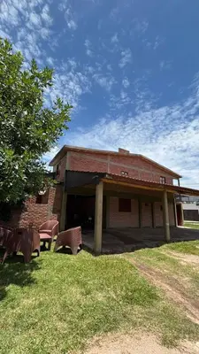 a brick building with two tables and chairs in the grass at Departamento Vilma Planta Baja Brochero in Villa Cura Brochero