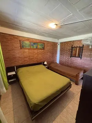 a bedroom with a bed and a brick wall at Departamento Vilma Planta Baja Brochero in Villa Cura Brochero