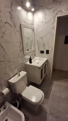 a bathroom with a white toilet and a sink at Hermosa Casa Moderna en el Mirador del Lago in Bialet Massé