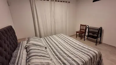 a bedroom with a bed and a chair and a window at Hermosa Casa Moderna en el Mirador del Lago in Bialet Massé